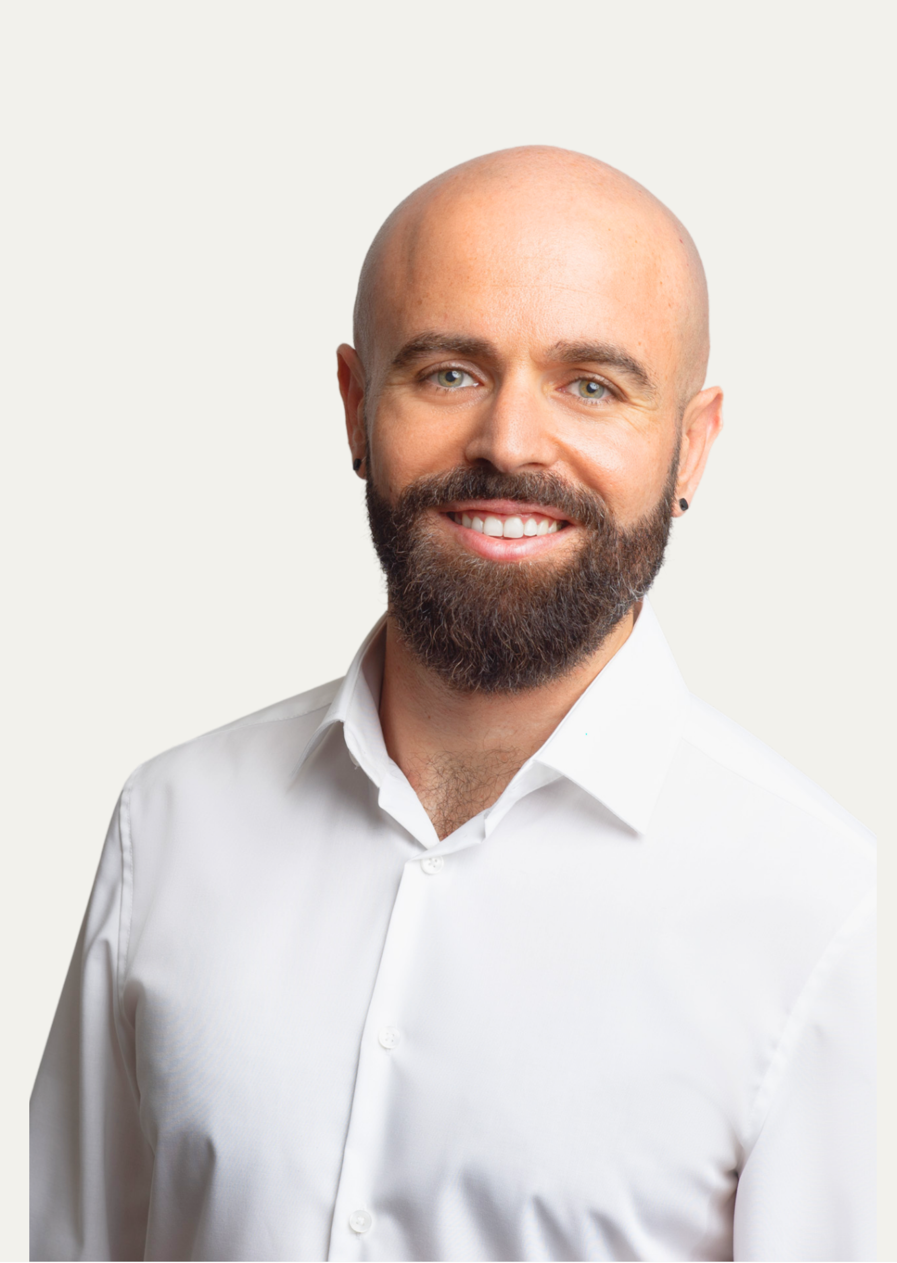 Lächelndes Porträt von mir, Pedro Biedma: ein bärtiger Mann mit rasiertem Kopf, grüne Augen und weißem Hemd. Der neutrale, helle Hintergrund unterstreicht mein freundliches und professionelles Erscheinungsbild.